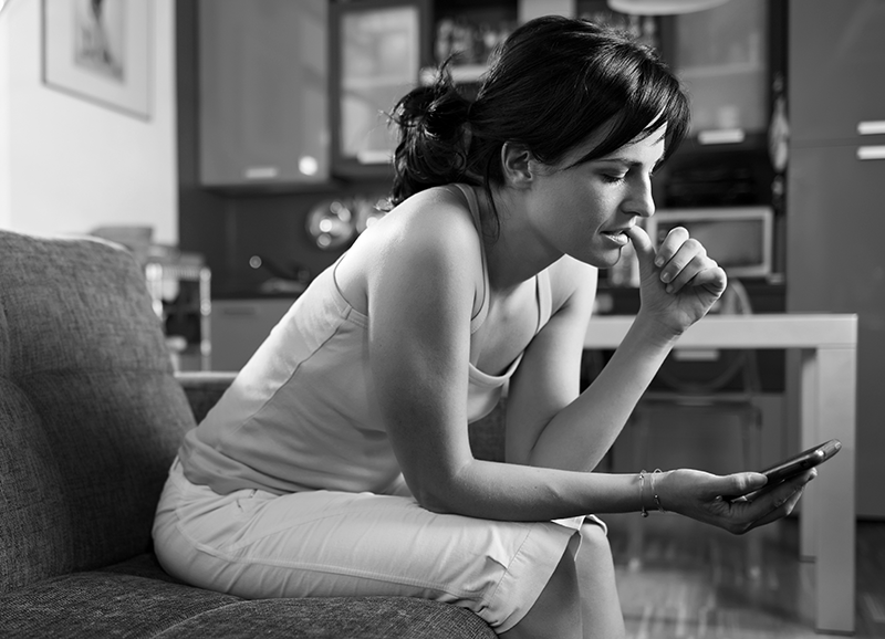 Woman lookin at phone biting her nail